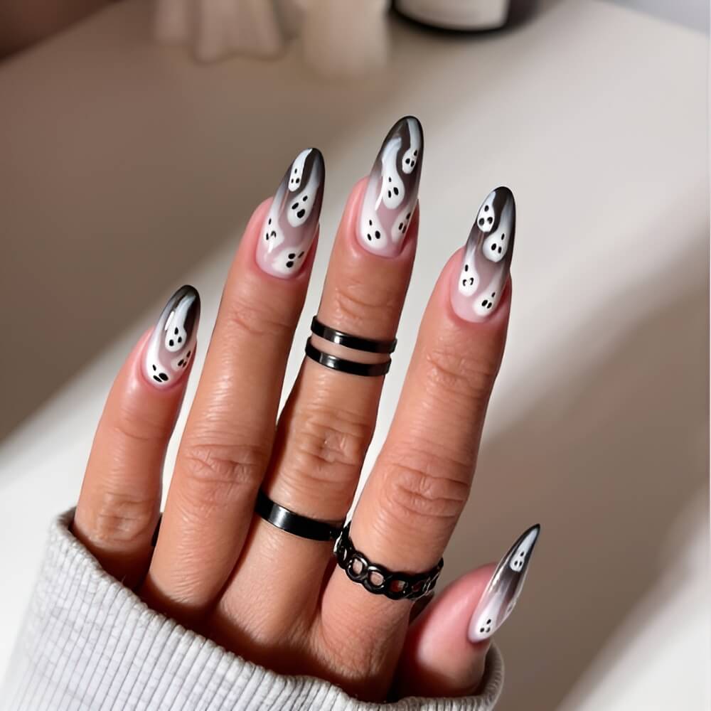 Faded black Halloween nails with white ghosts – trendy spooky nail design for October.