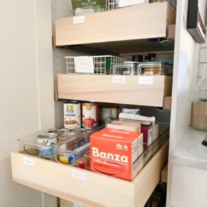 Pull-out drawers in a small pantry with organized canned goods and snacks. Small pantry organization