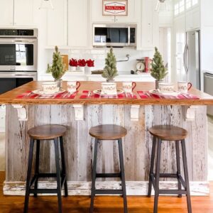 Holiday kitchen table decorated with Christmas linens, plaid runner, and festive touches.