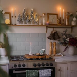 Rustic farmhouse Christmas kitchen decor with wood accents, candles, and greenery.