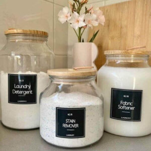 Minimal labeled containers and baskets organizing laundry supplies neatly on open shelves in a small laundry room. laundry room organization