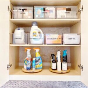 Stackable storage bins inside a laundry cabinet organizing cleaning supplies and small items.