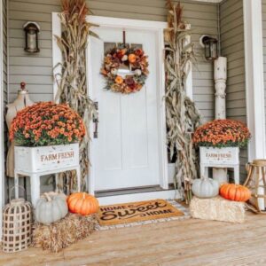 Matching black planters filled with autumn flowers framing a front door.