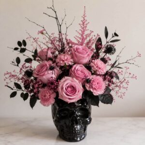 Pink roses and dark branches arranged in a black skull vase