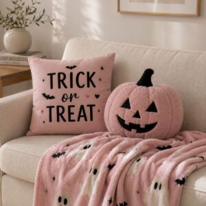 Cozy pink Halloween pillows and blanket styled on a sofa