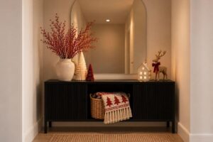 Console table decorated with a small Christmas tree and simple wooden holiday decorations.